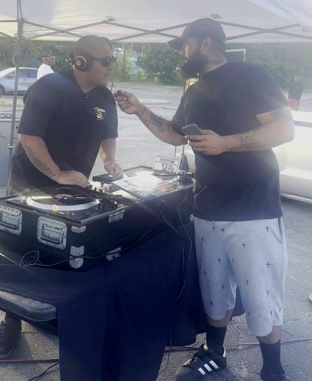 DJ in headphones spinning records under a canopy