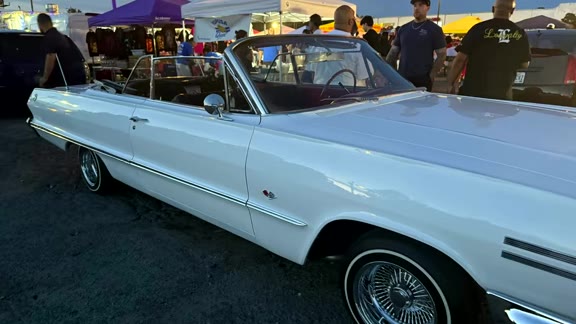 White classic convertible lowrider parked by the vendor tents